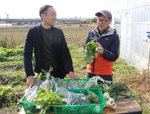 ＣＳＡで販売する旬の野菜を手にする大皿一寿さん（右）とロート製薬の戸崎亘さん＝神戸市西区玉津町二ツ屋