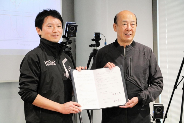 協定書を手にするアシックスの廣田康人社長（右）と兵庫県の斎藤元彦知事＝神戸市西区高塚台６、アシックススポーツ工学研究所