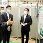 空気中のＣＯ２分離回収技術について、川崎重工業の橋本康彦社長（左端）の説明を受ける西村康稔経済産業相（右から２人目）＝１１日午前、明石市川崎町、同社明石工場