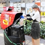 注文を受けたメニューを配送ロボットに積み込む飲食店スタッフ＝東京都新宿区