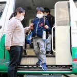 実証実験用のシューズを履いて送迎バスから降りる園児＝神戸市長田区大谷町２、神戸常盤大付属ときわ幼稚園