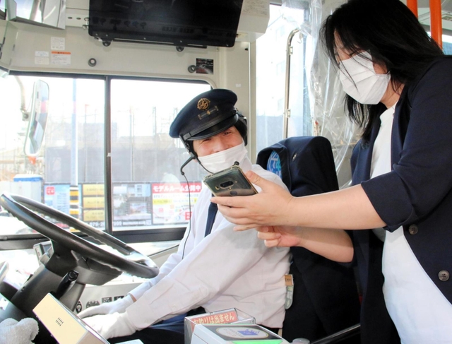 電子乗車券「ヒョウゴアメイジングパス」を表示したスマートフォンを運転手（左）に見せる訪日客の女性＝姫路市元町