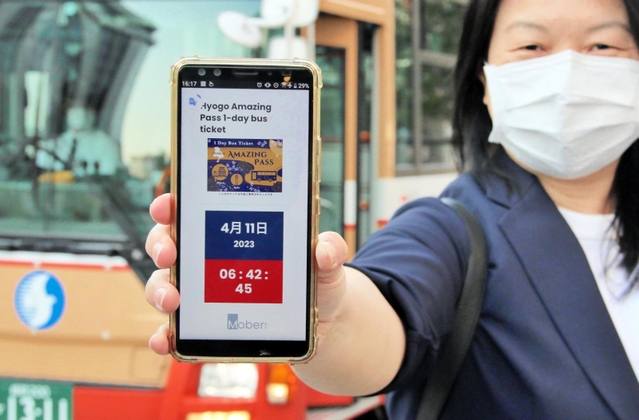 電子乗車券「ヒョウゴアメイジングパス」を表示したスマートフォンを持つ訪日客の女性＝姫路市駅前町