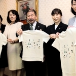 回収した包装紙や間伐材で作ったＴシャツを持つ関係者ら＝神戸市役所