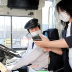 電子乗車券「ヒョウゴアメイジングパス」を表示したスマートフォンを運転手（左）に見せる訪日客の女性＝姫路市元町