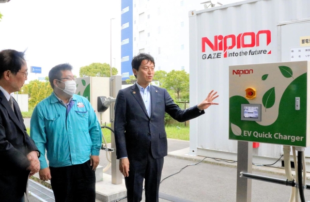 ニプロンの二見達也社長（左端）らからＥＶ充電器の説明を受ける兵庫県の斎藤元彦知事（右端）＝尼崎市大浜町２、同社