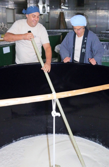 長い櫂（かい）棒でタンクのもろみを混ぜるカール・カルヴェルトさん（左）と杜氏の八島公玲さん＝丹波市市島町中竹田、西山酒造場