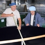 長い櫂（かい）棒でタンクのもろみを混ぜるカール・カルヴェルトさん（左）と杜氏の八島公玲さん＝丹波市市島町中竹田、西山酒造場