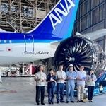 機体やエンジンを背にした、商品開発に携わった川崎重工業やＡＮＡホールディングスの社員ら＝羽田空港（川崎重工業提供）