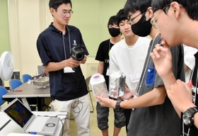 アルミホイルなどを巻き付けた容器の温度をサーモグラフィーで測定する高校生ら＝神戸市東灘区深江南町５、神戸大学深江キャンパス