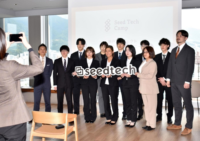 高原大輔社長（左端）、平井真哉ＣＴＯ（右端）とともに記念撮影するシードテックのプロジェクト参加者＝アンカー神戸