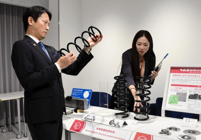 軽量化された自動車部品の説明を受ける斎藤元彦知事（左）＝神戸市西区高塚台１、神戸製鋼所神戸総合技術研究所