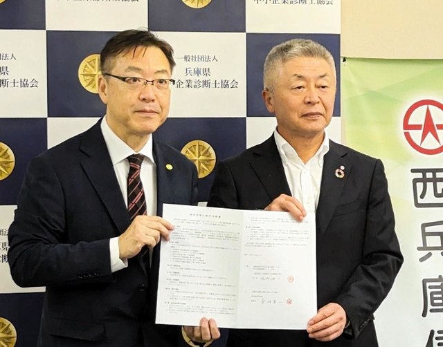 業務提携の覚書を手にする兵庫県中小企業診断士協会の湯浅伸一会長（左）と西兵庫信用金庫の桑垣喜一理事長＝神戸市中央区東川崎町１（同協会提供）