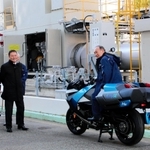 神戸・ポートアイランドの水素発電実証施設を視察し、水素エンジンを搭載した研究用バイクにまたがる菅義偉前首相（右端）＝２５日午後、神戸市中央区港島中町８