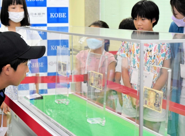 昨年夏の親子見学会で、新紙幣をのぞき込む子どもたち＝２０２３年７月、神戸市中央区京町、日銀神戸支店