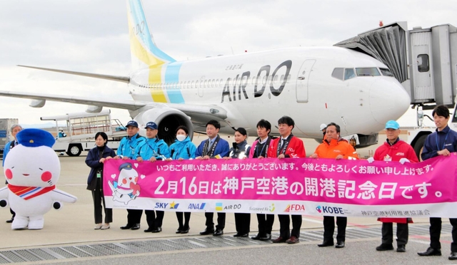 開港記念日を祝い、横断幕を広げる航空会社などの社員ら＝神戸空港