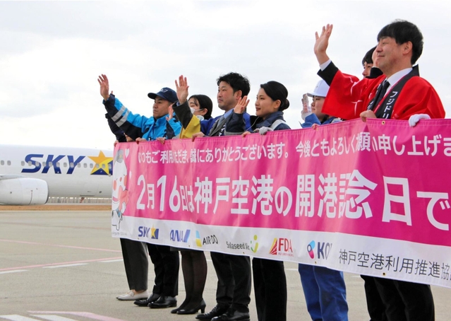 開港記念日を祝い、横断幕を広げる航空会社などの社員ら＝神戸空港