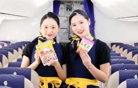 スカイマーク機内で３月から販売される「鴬ボール」と「ミニしるこサンド」をＰＲする同社の客室乗務員（同社提供）