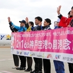 開港記念日を祝い、横断幕を広げる航空会社などの社員ら＝神戸空港