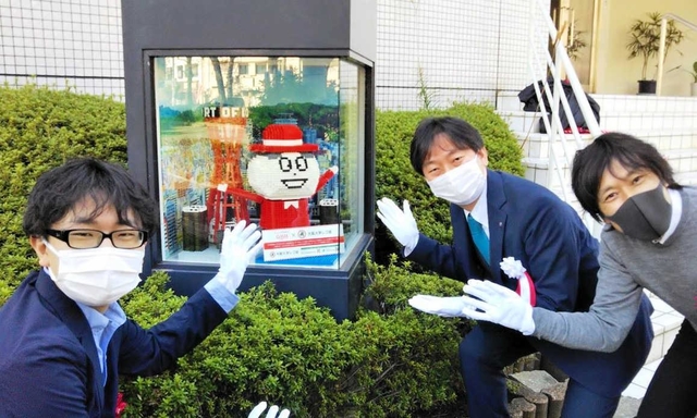 レゴでできた「Ｑちゃん」を囲む、（左から）北山智也さん、塚本浩康副社長、山崎秀昭さん＝神戸市中央区坂口通１