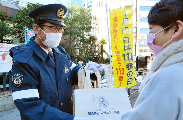 エコバッグを配り、１１０番の適正利用を呼び掛ける警察官（左）＝神戸市中央区布引町４
