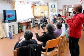 テレビ画面を見ながら体操をする高齢者＝神戸市長田区大橋町９