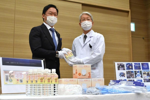 西村公秀社長（左）から支援物資を受け取る木原康樹院長＝神戸市中央区港島南町２