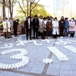 並べたキャンドルの前で、東日本大震災の犠牲者に黙とうをささげる人々＝神戸市中央区加納町６