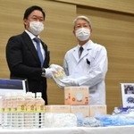 西村公秀社長（左）から支援物資を受け取る木原康樹院長＝神戸市中央区港島南町２