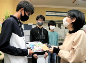 バリアフリーマップの啓発ポスターを配って回る灘中学校の生徒（左）＝神戸市東灘区