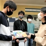 バリアフリーマップの啓発ポスターを配って回る灘中学校の生徒（左）＝神戸市東灘区