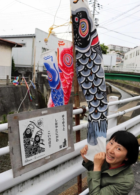 「しおやカルタ」の絵札をデザインした大竹奈緒子さんと、塩屋谷川のそばに設置された大判かるた＝神戸市垂水区塩屋町３