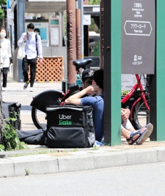 注文がなく、座り込んで待機する「地蔵」状態の配達員＝神戸市中央区加納町４