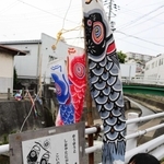 「しおやカルタ」の絵札をデザインした大竹奈緒子さんと、塩屋谷川のそばに設置された大判かるた＝神戸市垂水区塩屋町３