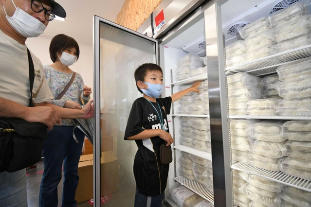 オープンした無人販売所で、冷凍庫からギョーザを取り出す来店客＝神戸市西区白水２