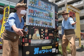 長田中央市場前にお目見えした自動販売機。寅さんにふんしたファンが駆けつけ、設置を祝った＝神戸市長田区六番町８