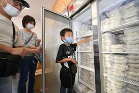 オープンした無人販売所で、冷凍庫からギョーザを取り出す来店客＝神戸市西区白水２