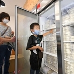 オープンした無人販売所で、冷凍庫からギョーザを取り出す来店客＝神戸市西区白水２