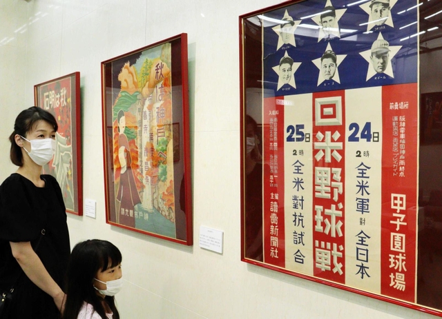 星条旗をモチーフにした日米野球のポスターを見る親子＝東灘区田中町５、コープこうべ生活文化センター