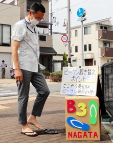 手作りの靴箱を仮置きし、長田区と須磨区の境でビーチサンダルに履き替える長田区の増田匡区長＝神戸市長田区松野通４