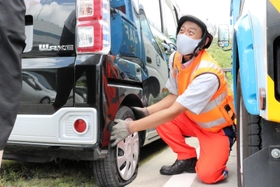 パンク時の状況を聞きながら、タイヤ交換の説明をする伊藤直宏さん＝神戸市北区