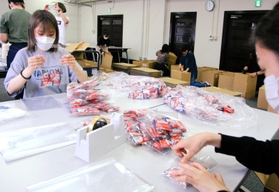 困窮する子育て世帯に送る菓子を袋詰めしたり、段ボールを組み立てたりする大学生ら＝神戸市中央区小野浜町