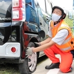 パンク時の状況を聞きながら、タイヤ交換の説明をする伊藤直宏さん＝神戸市北区