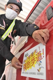 啓発用のステッカーを集配車に貼る郵便局員＝神戸市長田区細田町７、長田郵便局