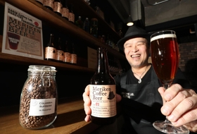 香り高くフルーティーな味わいの「メリケンコーヒービール」を手にする大西賢さん＝神戸市灘区水道筋６
