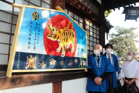 大待雄治郎さん（左）が制作し、丹生神社に奉納された絵馬。疫病退散を願って、張り子の虎が大きく描かれている＝神戸市灘区高羽町４