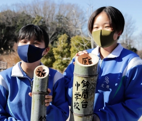 切った竹に筆で文字を書き入れた生徒たち＝神戸市北区山田町藍那、あいな里山公園