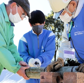ボランティアに教えてもらいながら竹を灯籠の大きさに切る生徒＝神戸市北区山田町藍那、あいな里山公園