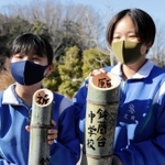 切った竹に筆で文字を書き入れた生徒たち＝神戸市北区山田町藍那、あいな里山公園