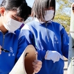 切った竹に筆で文字を書き入れる生徒たち＝神戸市北区山田町藍那、あいな里山公園